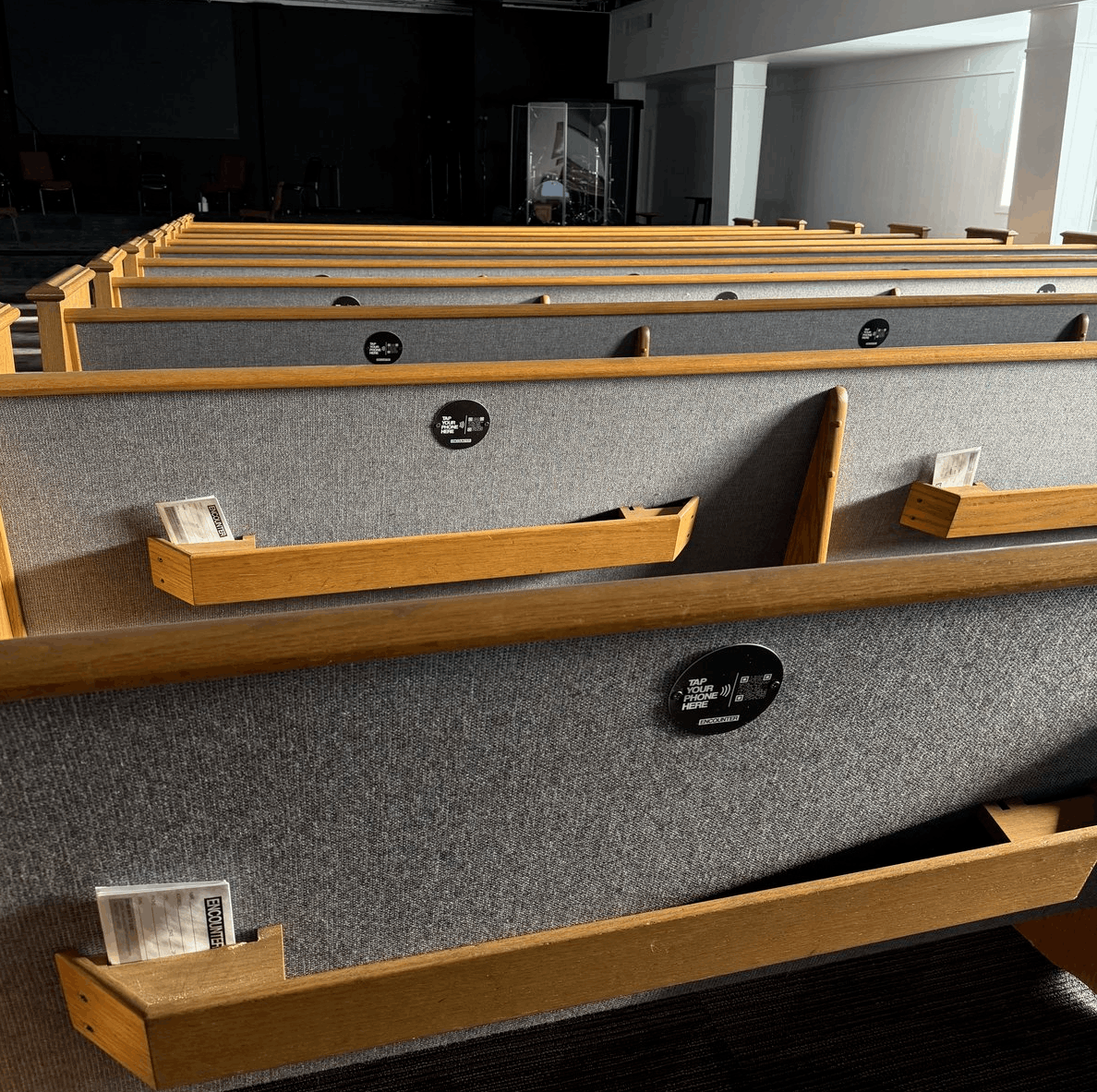 NFC tap-to-give plates mounted on church pew backs in a real church sanctuary