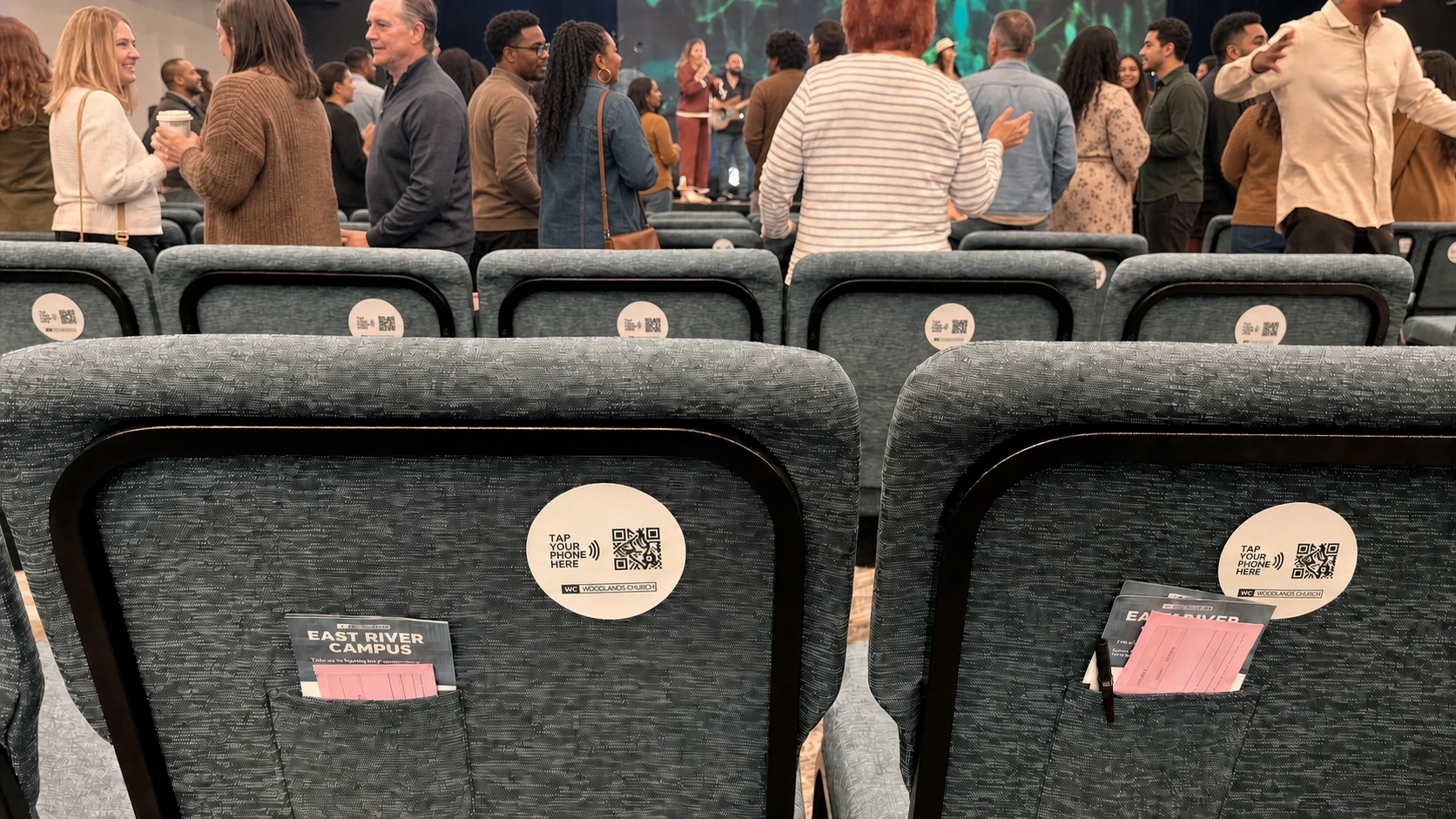 Rows of church auditorium chairs fitted with NFC tap-to-give plates, congregation gathered behind