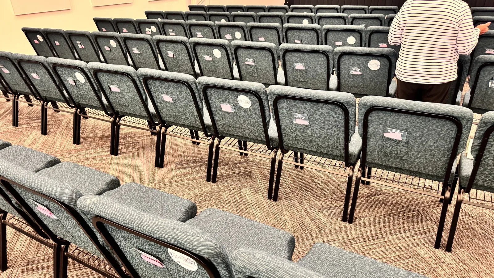 Rows of stadium chairs in a non-denominational church auditorium with NFC tap plates ready for tap to give and tap to donate